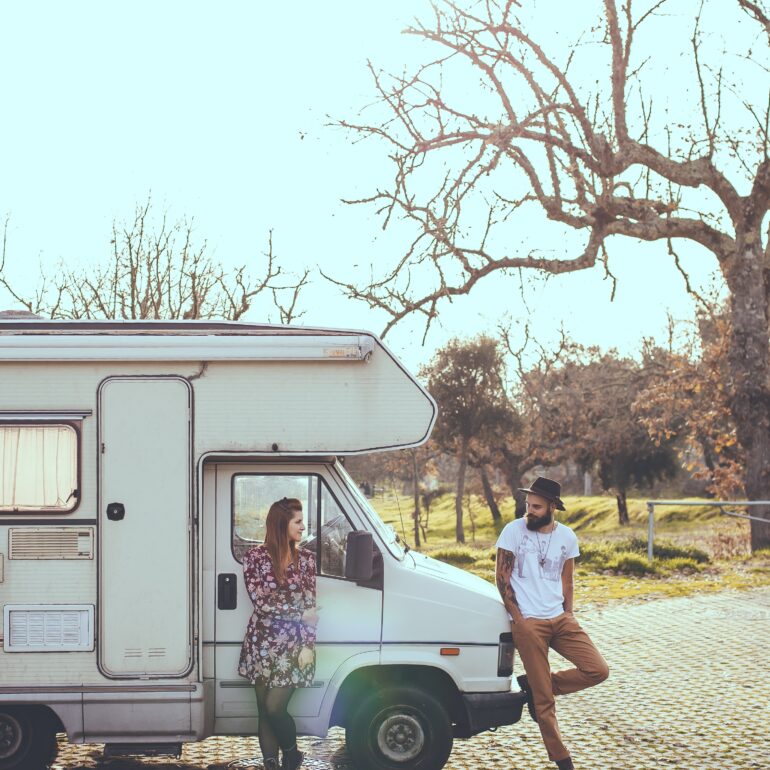 Homme et femme qui se regardent en étant adossé à un camping-car